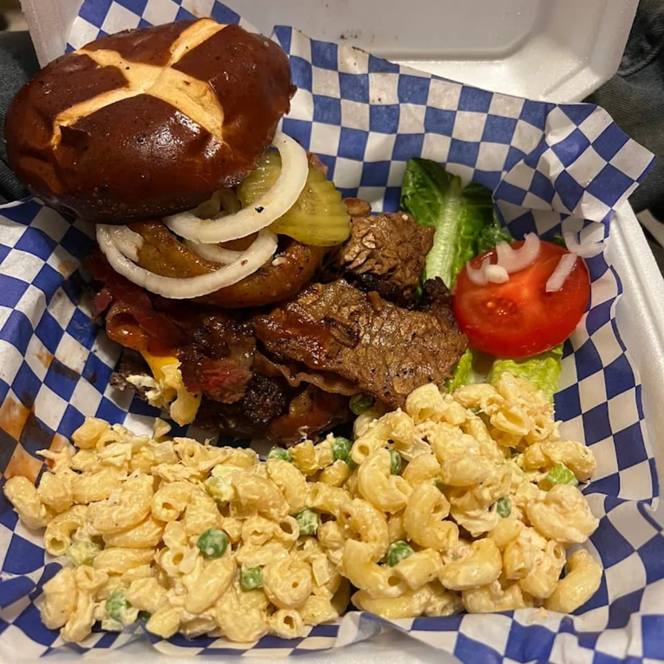 Smokey Sensations' BBQ brisket sandwich on a pretzel bun with macaroni salad and a side salad.